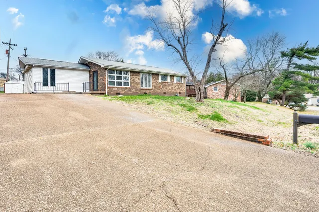a front view of a house with a garden and trees