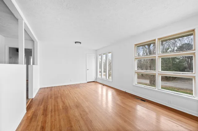 a view of an empty room with wooden floor and windows