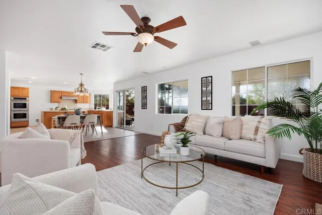 a living room with furniture kitchen view and a wooden floor