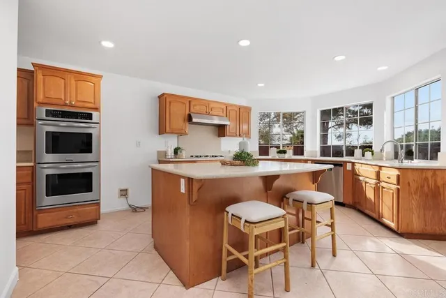 a kitchen with stainless steel appliances granite countertop a stove a sink a oven a dining table and chairs