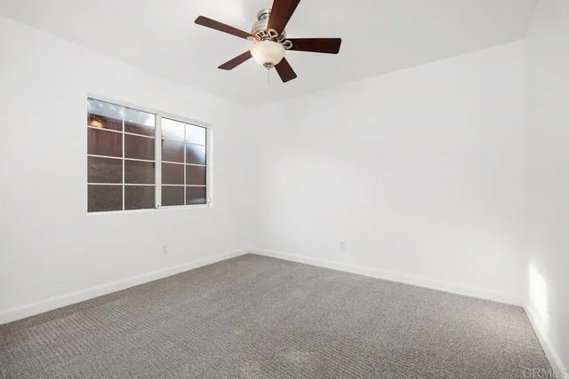 an empty room with a window and a ceiling fan