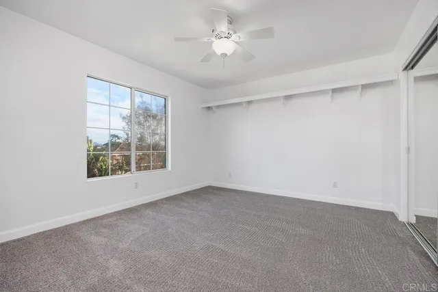 an empty room with a window and a ceiling fan