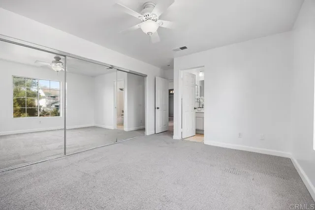 an empty room with closet and a ceiling fan
