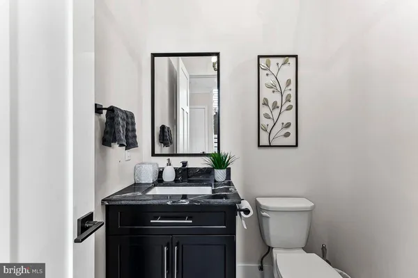 a bathroom with a granite countertop toilet sink and mirror