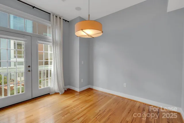 a view of an empty room with window and wooden floor