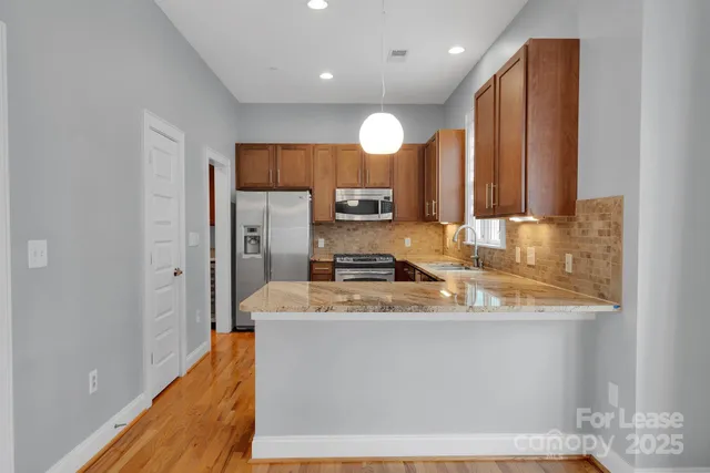 a large kitchen with stainless steel appliances granite countertop a sink a stove and a refrigerator