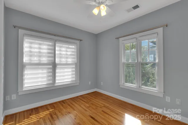 a view of an empty room with window and wooden floor