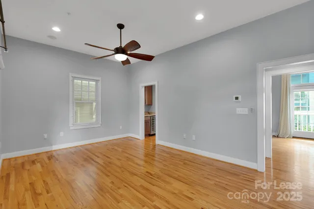 a view of an empty room with window and wooden floor