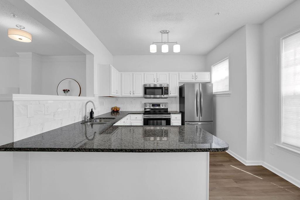 215 Riverstone Commons Circle Canton, GA 30114 - Photo 17 of 36 a kitchen with granite countertop stainless steel appliances a sink a refrigerator a stove a counter space and cabinets