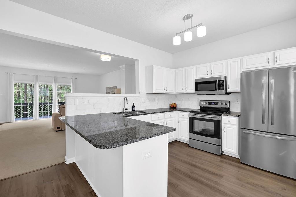 215 Riverstone Commons Circle Canton, GA 30114 - Photo 18 of 36 a kitchen with a center island wooden floor and stainless steel appliances