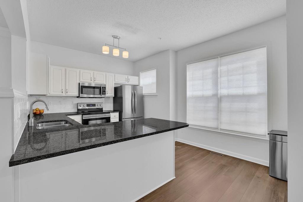 215 Riverstone Commons Circle Canton, GA 30114 - Photo 21 of 36 a kitchen with granite countertop a refrigerator and a stove top oven