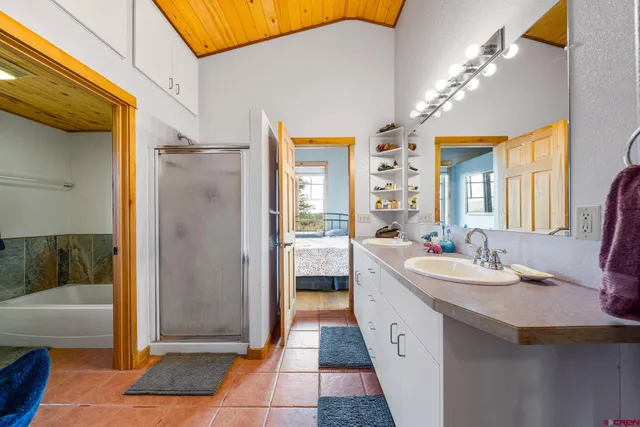 a spacious bathroom with a double vanity sink a mirror and a bathtub