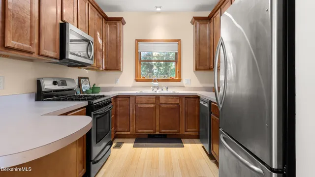 a kitchen with stainless steel appliances granite countertop a refrigerator a stove a sink and a microwave