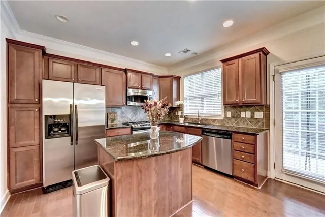 a kitchen with stainless steel appliances granite countertop a sink stove refrigerator and cabinets