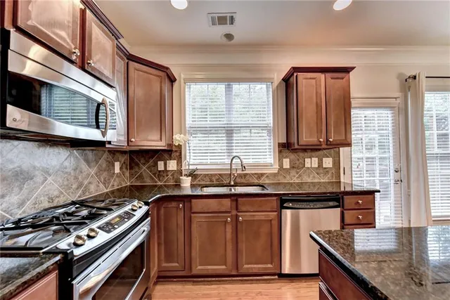 a kitchen with stainless steel appliances granite countertop a stove a sink and a microwave