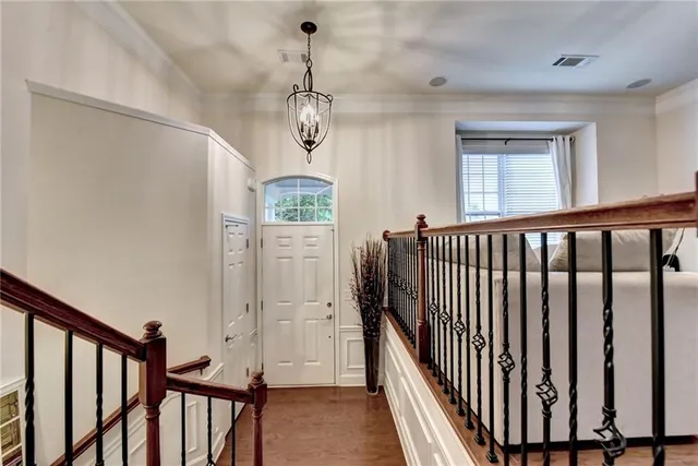 a view of a hallway with wooden floor and chandelier