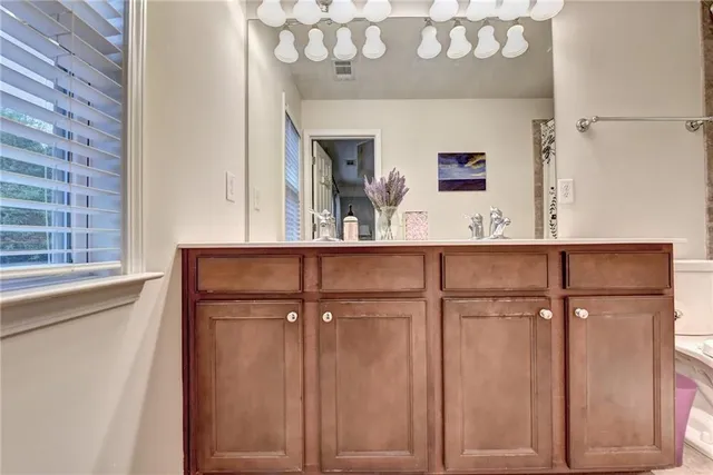 a bathroom with a sink a large mirror and a light fixture