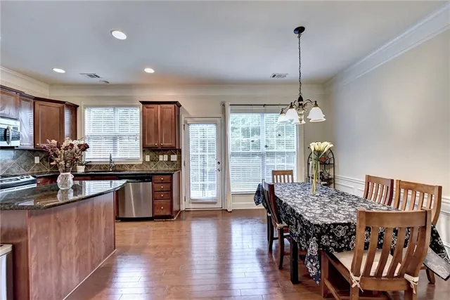 a kitchen with stainless steel appliances granite countertop a kitchen island hardwood floor sink stove dining table and chairs