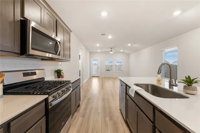 a kitchen with stainless steel appliances granite countertop a sink a stove top oven and wooden floor