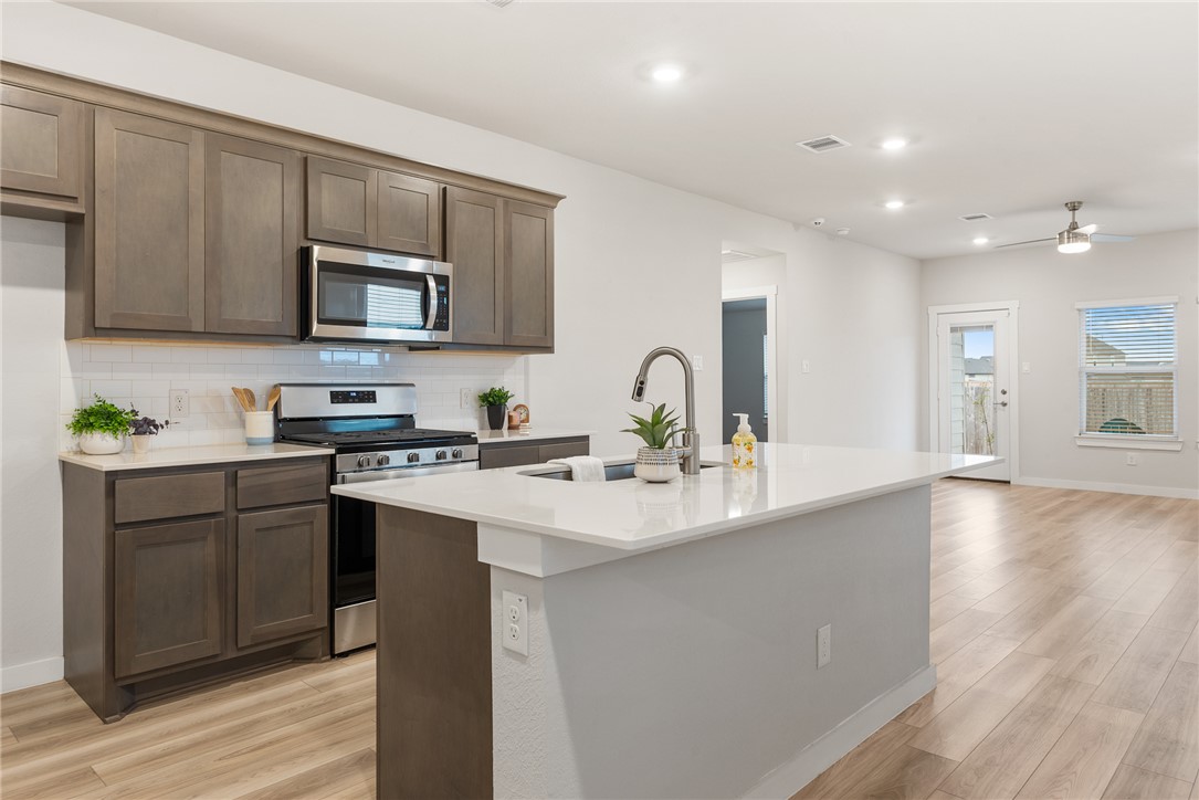 918 Kickapoo Lane College Station, TX 77845 - Photo 8 of 31 a kitchen with stainless steel appliances a sink dishwasher a stove top oven a refrigerator with white cabinets and wooden floor
