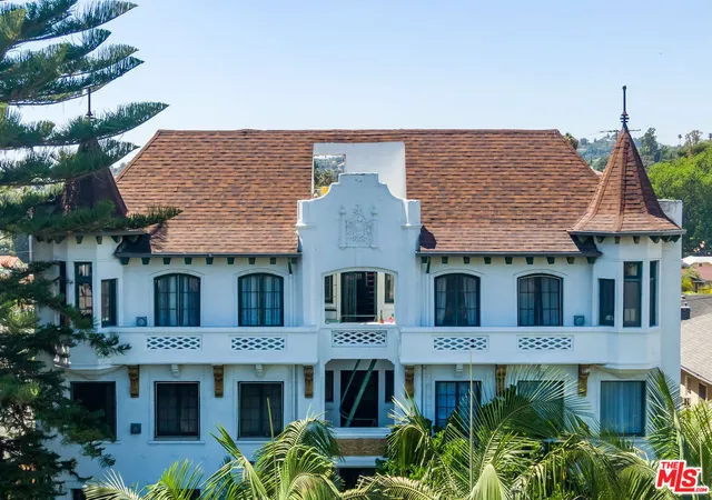 a front view of a house with plants and large tree