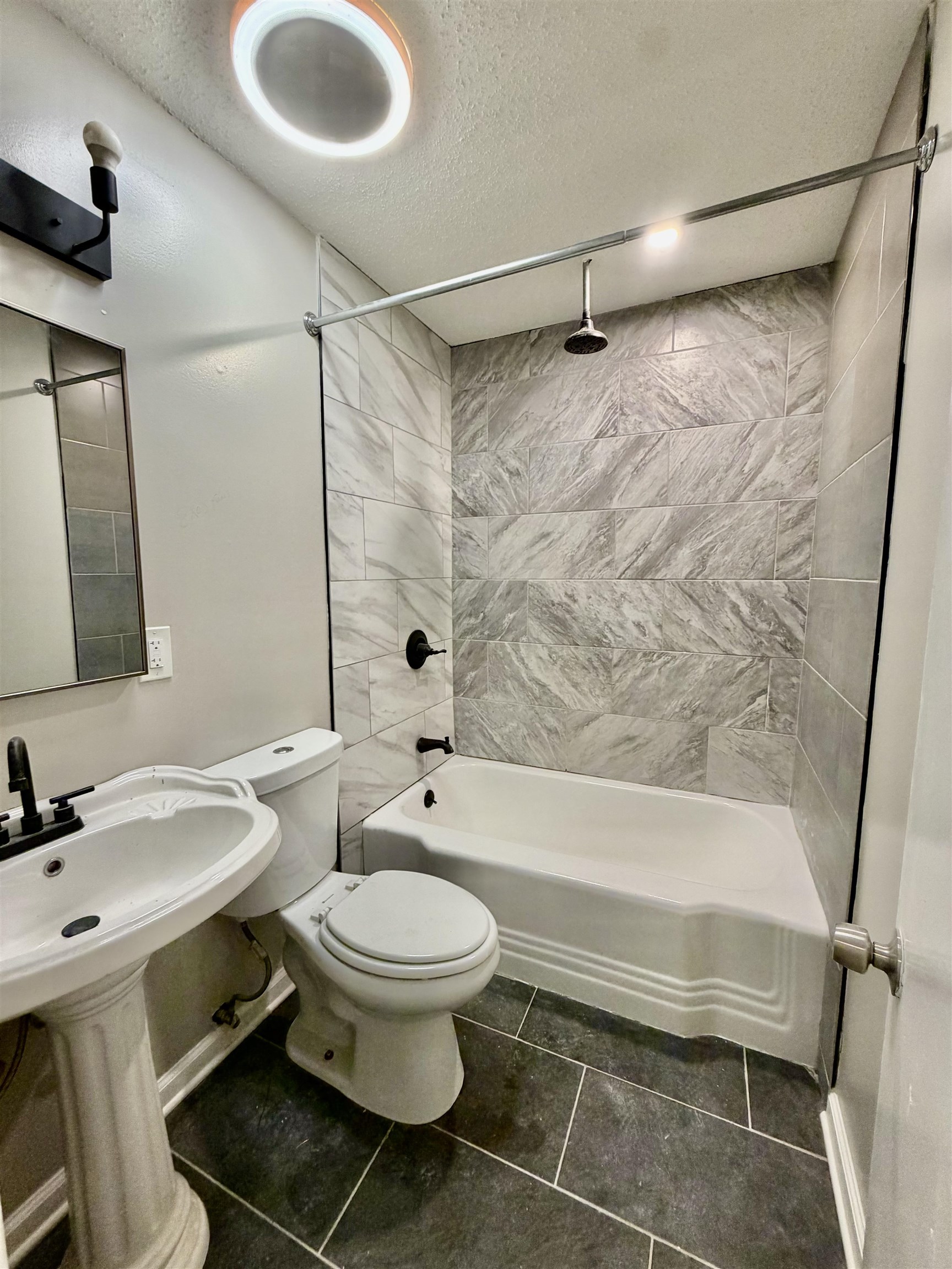 Bathroom featuring a combined bath / shower with rainfall shower and a textured ceiling
