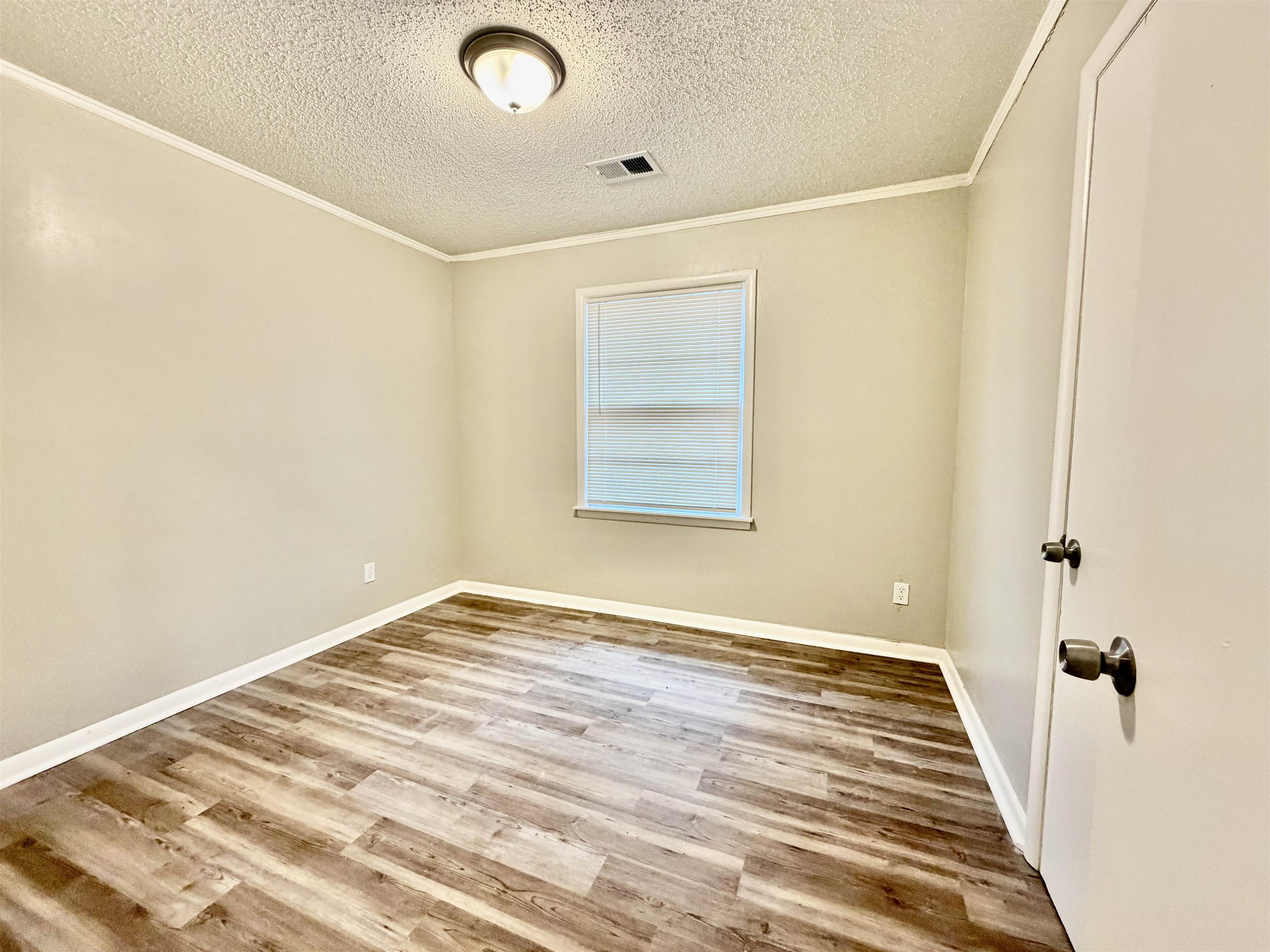 3345 Charlotte Road Memphis, TN 38109 - Photo 4 of 10 Bedroom with light wood finished floors, a textured ceiling, and crown molding