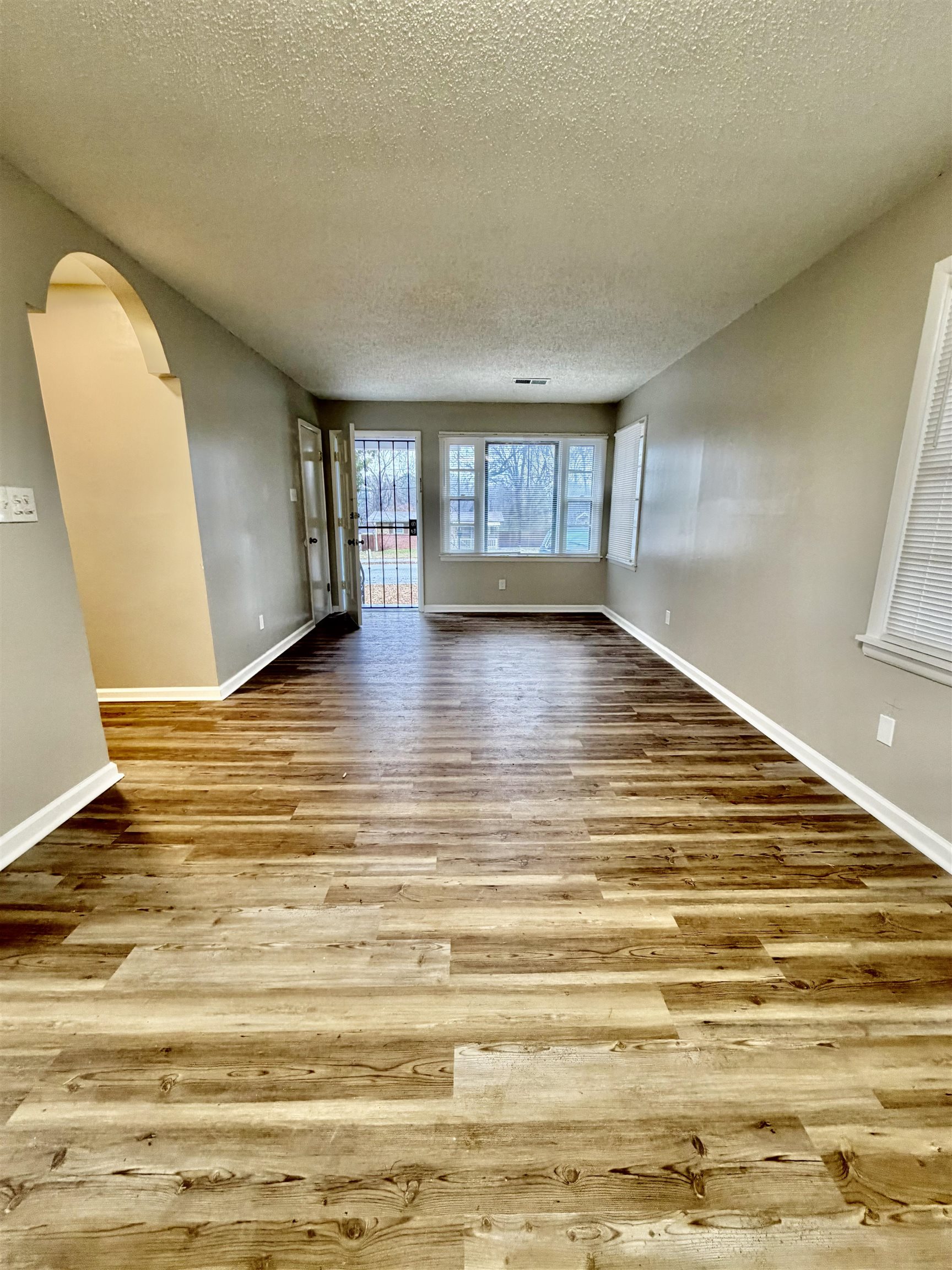 3345 Charlotte Road Memphis, TN 38109 - Photo 7 of 10 Empty room featuring arched walkways, a textured ceiling, and light wood-style floors