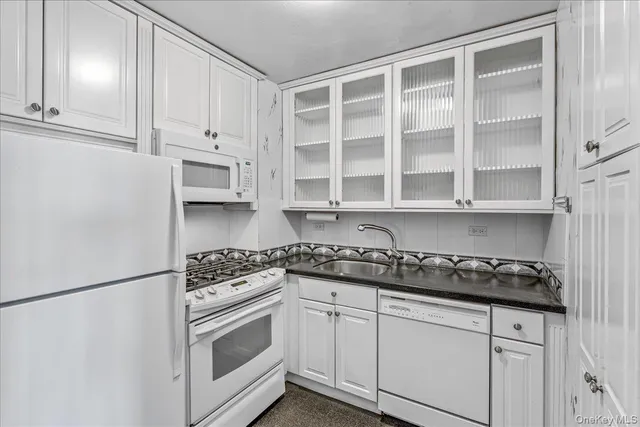 a kitchen with white cabinets and appliances