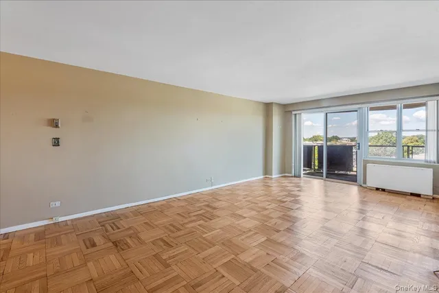 a view of an empty room with a window and a kitchen
