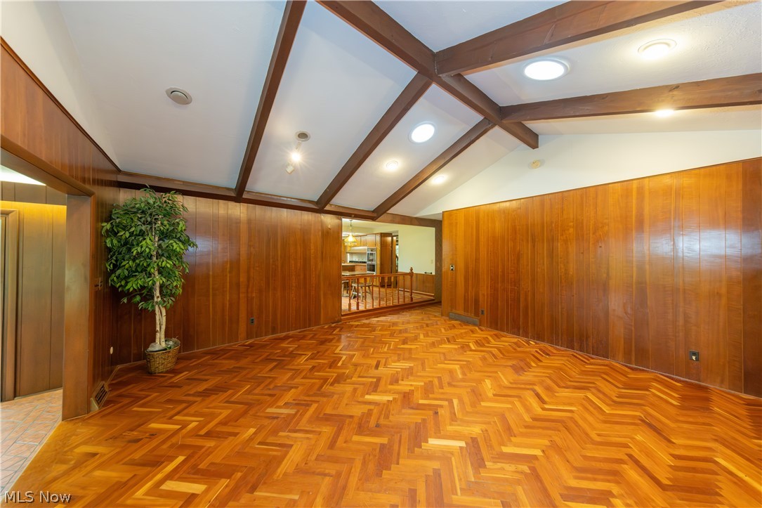 25001 Letchworth Road Beachwood, OH 44122 - Photo 17 of 50 Spacious room featuring herringbone wood-finish flooring, wood paneling, and a vaulted ceiling with exposed beams
