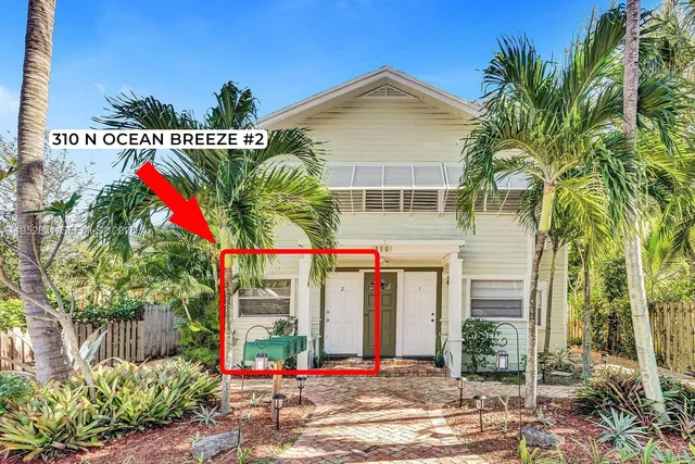 a front view of multi story residential apartment building with yard and sign board