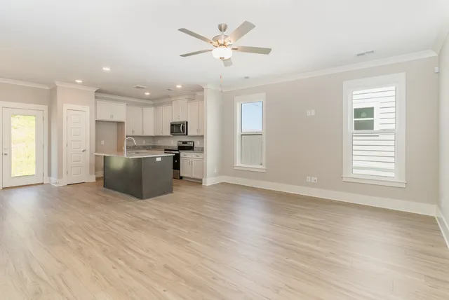 a view of a kitchen with a stove cabinets a ceiling fan and wooden floor