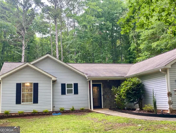a view of a house with a yard plants and large tree