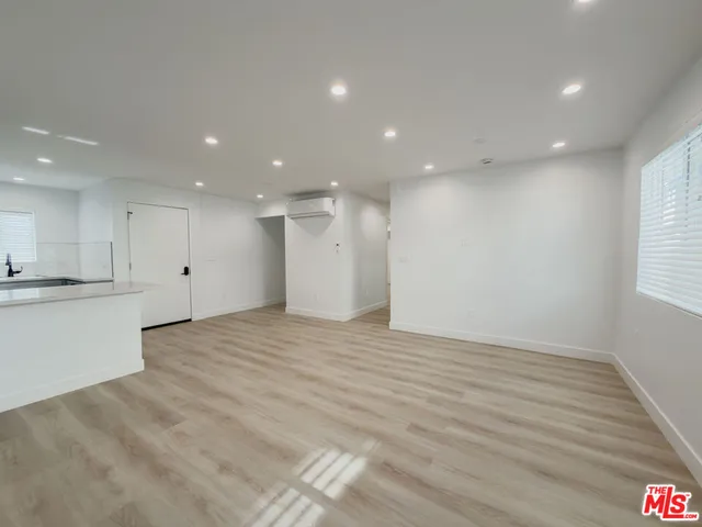 a view of an empty room with kitchen and window