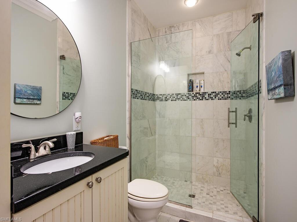 11231 Keewaydin Island Naples, FL 34113 - Photo 11 of 27 a bathroom with a granite countertop sink a toilet a mirror and shower