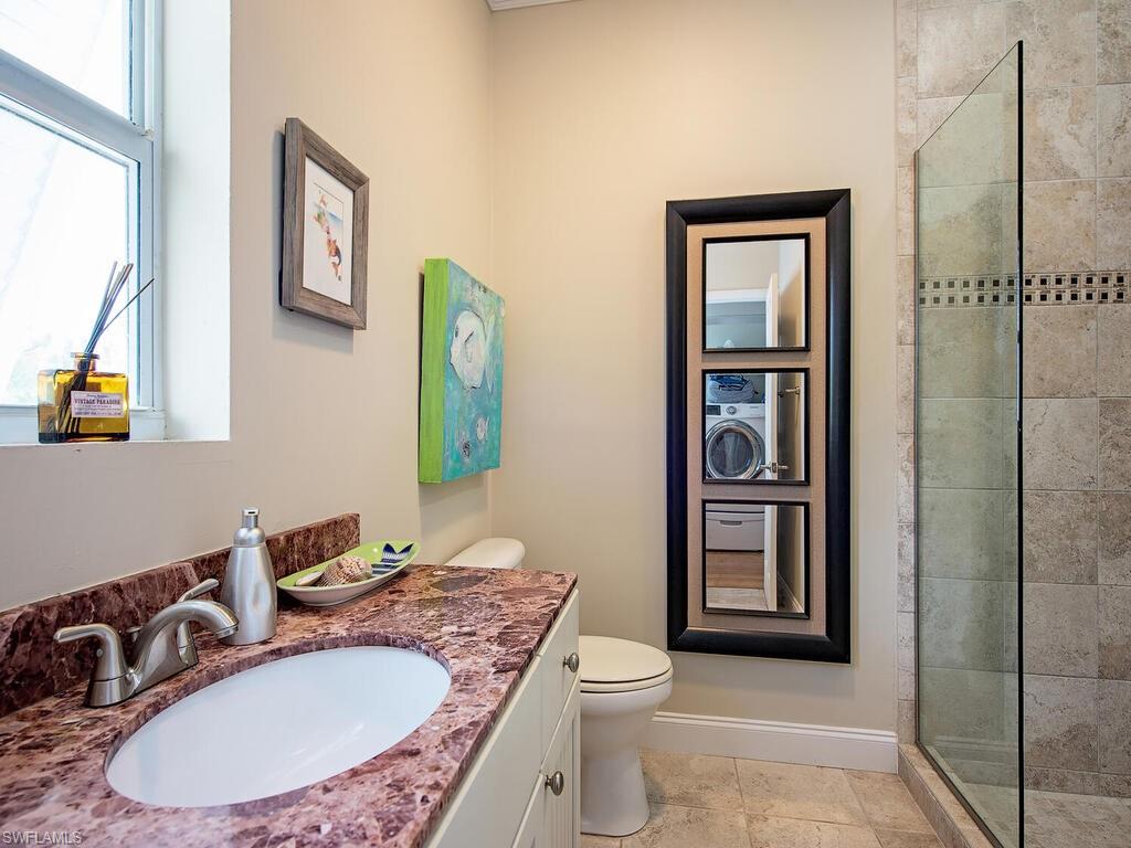 11231 Keewaydin Island Naples, FL 34113 - Photo 12 of 27 a bathroom with a granite countertop sink a toilet a mirror and shower