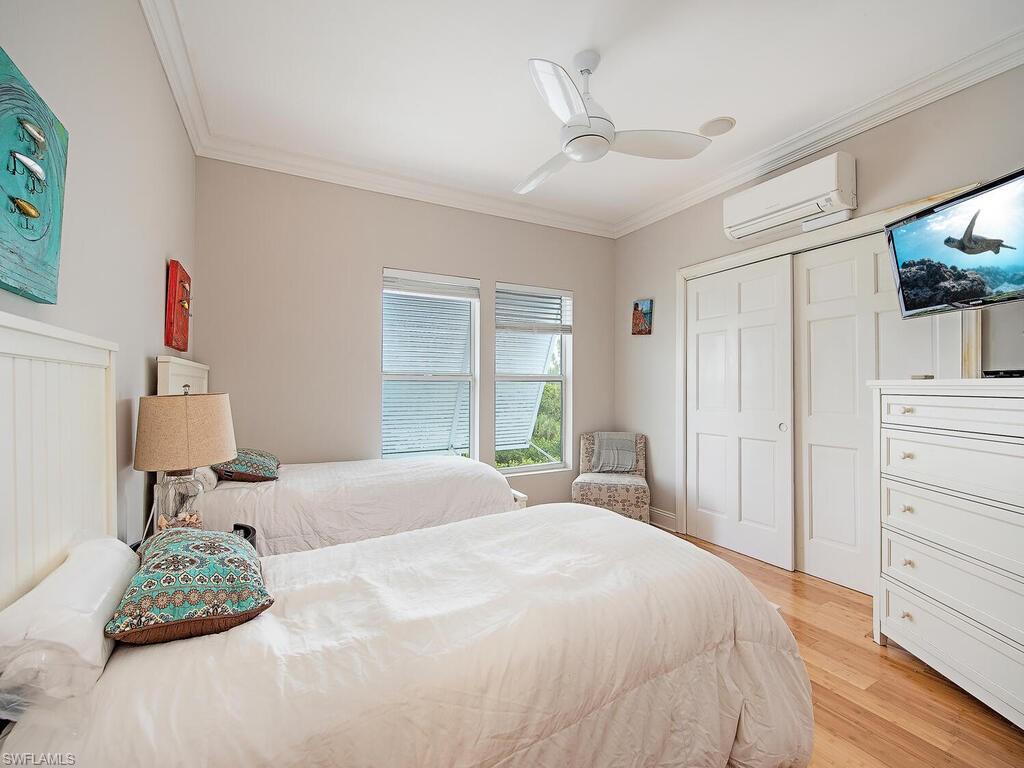 11231 Keewaydin Island Naples, FL 34113 - Photo 9 of 27 a spacious bedroom with a bed a window and potted plant on the dresser