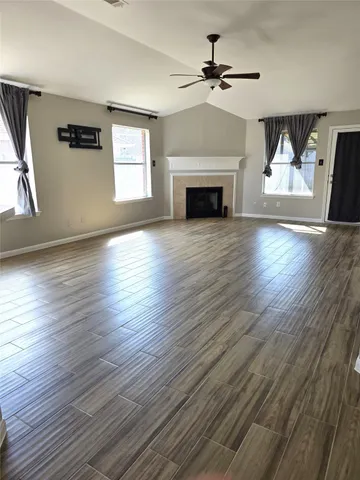 an empty room with wooden floor fireplace and windows