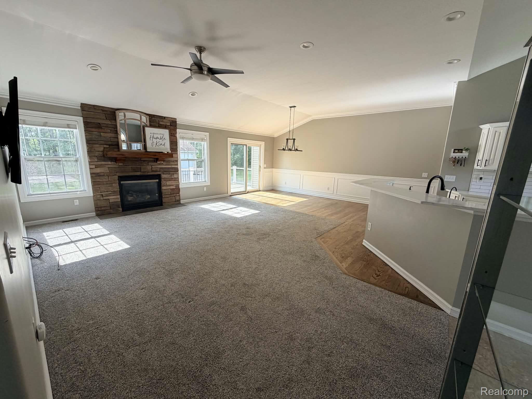 10070 Fenton Road Fenton, MI 48430 - Photo 3 of 21 Vaulted ceilings with recessed lighting, stone-clad fireplace, wood-finish flooring, and a kitchen island with sink