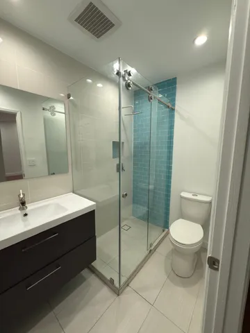 a bathroom with a shower sink mirror and toilet