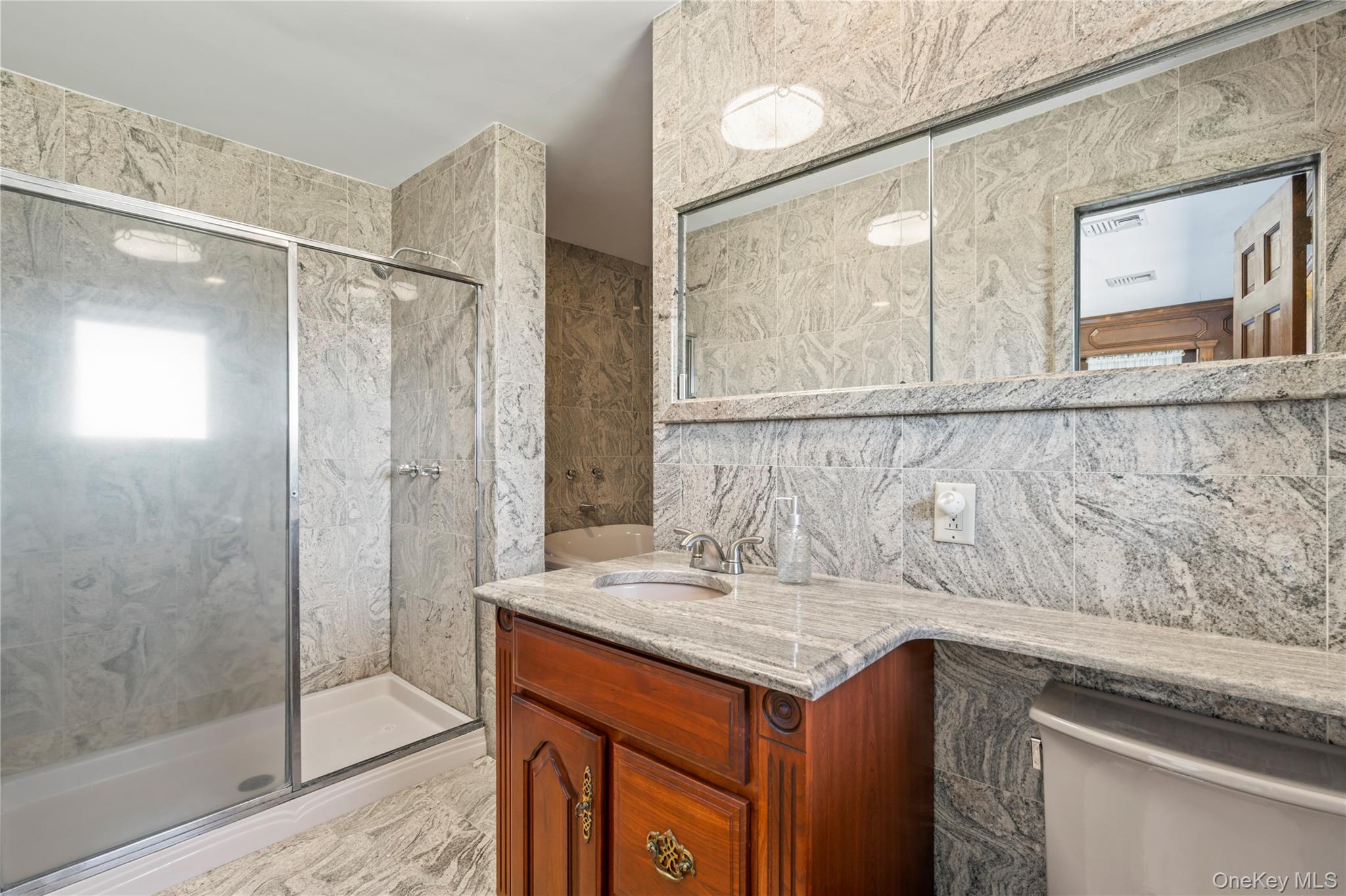 22 Messenger Lane Sands Point, NY 11050 - Photo 27 of 49 a bathroom with a granite countertop sink a mirror and a shower