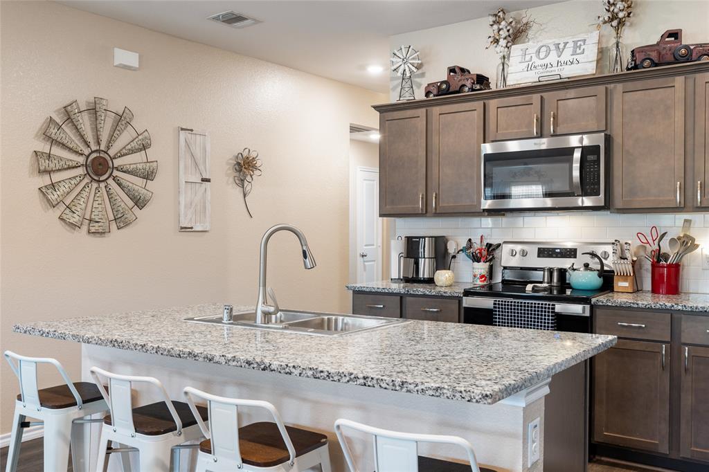 173 Seabiscuit Road Caddo Mills, TX 75135 - Photo 11 of 40 a kitchen with granite countertop a sink and a stove top oven with wooden floor