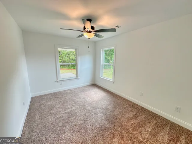 an empty room with windows and fan