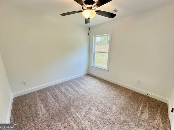 an empty room with a window and a fan