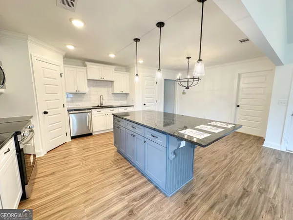 a large kitchen with stainless steel appliances granite countertop a large stove a sink dishwasher and a wooden floor