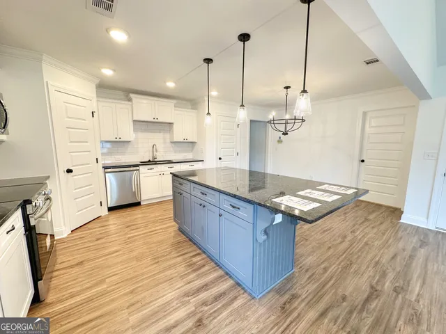 a large kitchen with stainless steel appliances granite countertop a large stove a sink dishwasher and a wooden floor