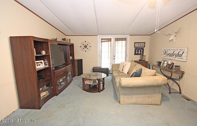 54170 Vontz Road East Callahan, FL 32011 - Photo 5 of 24 a living room with furniture a flat screen tv and a refrigerator
