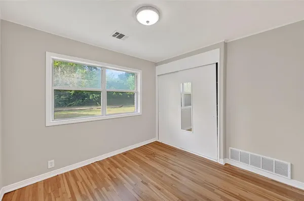 an empty room with wooden floor and windows