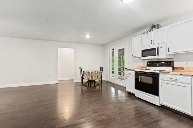 a kitchen with stainless steel appliances a stove top oven a sink dishwasher and a refrigerator with wooden floor